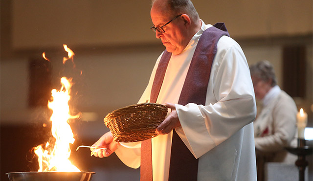 FATHER THOMAS KOMMERS OF ST. JOSEPH CHURCH IN RED WING, MINN., PUTS PALMS IN A BOWL AND BURNS THEM DURING AN ASH WEDNESDAY PRAYER SERVICE FEB. 10. / PHOTO: (CNS PHOTO/DAVE HRBACEK, THE CATHOLIC SPIRIT)